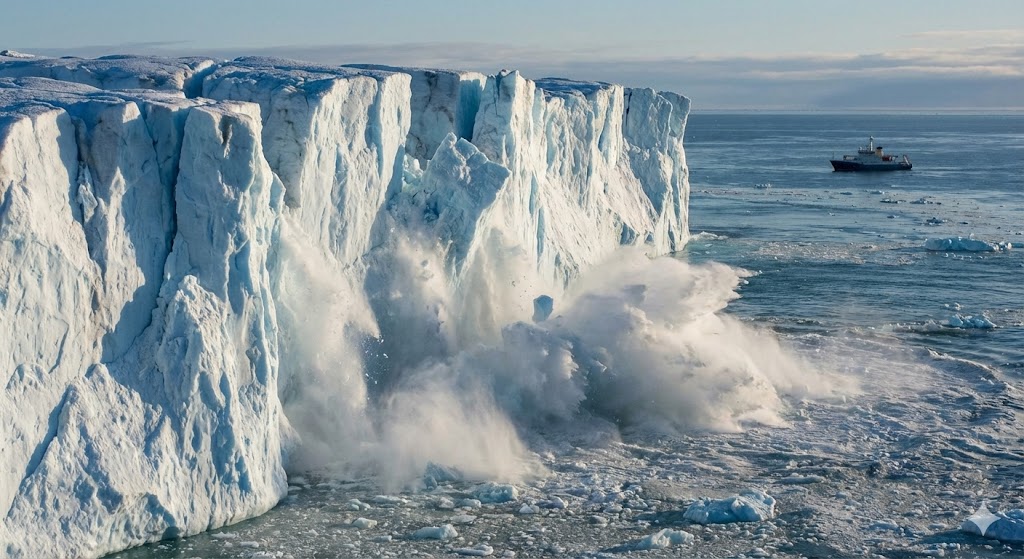 Un'immagine documentaristica mostra il drammatico scioglimento dei ghiacci in Groenlandia con il distacco di una parete glaciale nell'oceano.